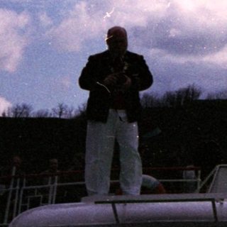Person conducting boat under elevated bridge.