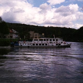 River cruise boat passing through scenic town.