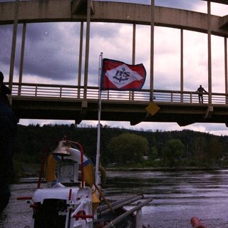Curved bridge over river with pedestrians, boat below.