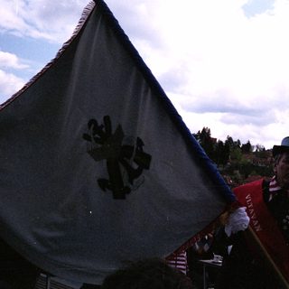 Man in traditional uniform holding flag near water.