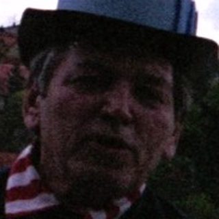 Man in traditional uniform holding flag near water.
