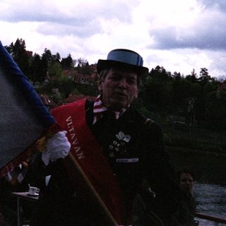 Man in traditional uniform holding flag near water.