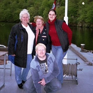 Four people posing together near a dock by water.