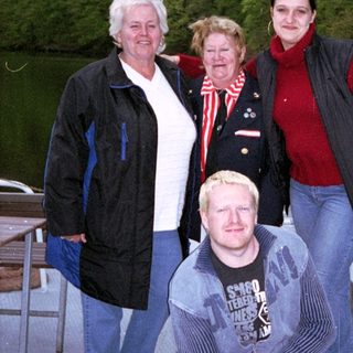 Four people posing together near a dock by water.