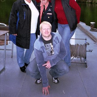 Four people posing together near a dock by water.