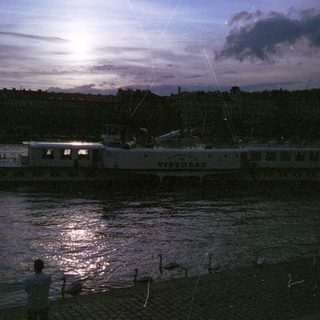 Moonlit night scene by water with silhouetted figures.