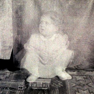 Vintage photo of child sitting on train model.