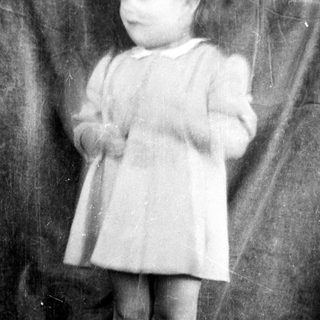 Young child in vintage dress standing indoors.