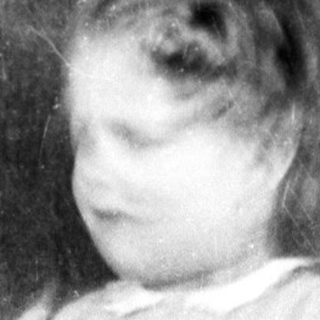 Young child in vintage dress standing indoors.