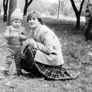 A woman and young child posing outdoors in park.