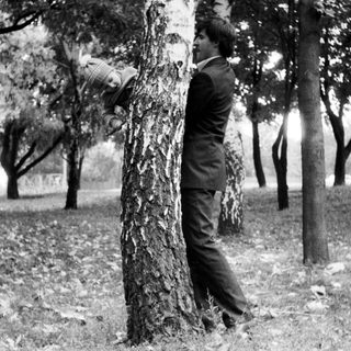 A man leaning against a tree in a park.