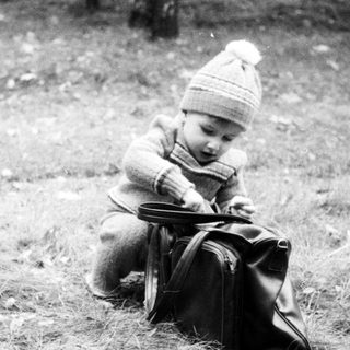 Child playing with a suitcase outdoors.