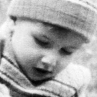 Child playing with a suitcase outdoors.