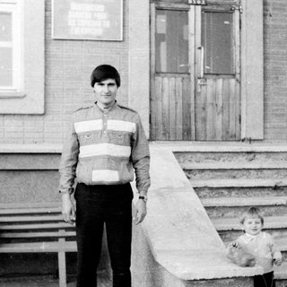 A man and young child standing outside on steps.