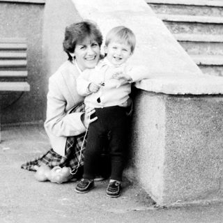 A woman holding a young child outdoors.