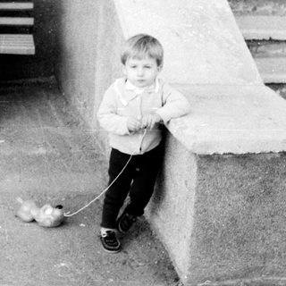 Young boy walks dog on leash outdoors.