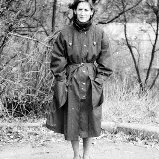 Woman in vintage coat standing outdoors on path.