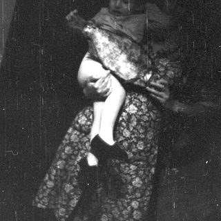 A person in vintage clothing holding a child.
