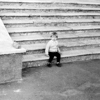 A child sitting alone on concrete steps.