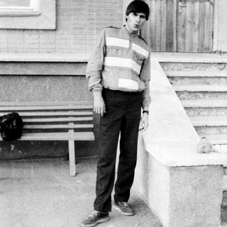 Young man standing on stairs in casual 1970s-style clothing.