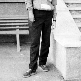 Young man standing on stairs in casual 1970s-style clothing.