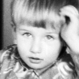 Young child standing indoors near bucket.