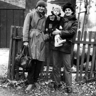 Family posing outdoors in winter clothing, holding baby.