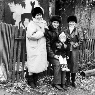 Three women and a baby outdoors in winter attire.