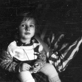Child holding stuffed animal in dim lighting.