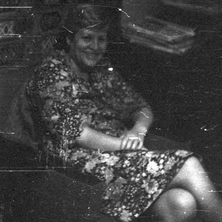 Vintage black-and-white photo of woman sitting indoors.