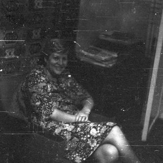Vintage black-and-white photo of woman sitting indoors.