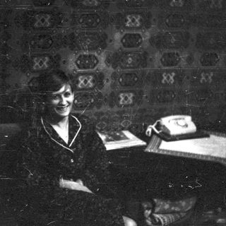 Vintage black-and-white photo of woman at rotary phone.