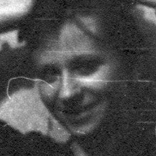 Vintage black-and-white photo of person laughing indoors.