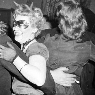 People dancing at a party, one in horned costume.