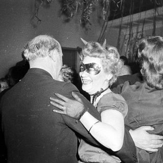 People dancing at a party, one in horned costume.