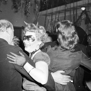 People dancing at a party, one in horned costume.