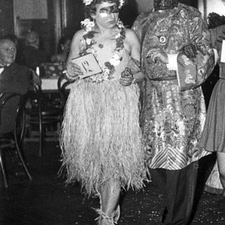 Costumed party attendees in 1940s-style masks and themed outfits.