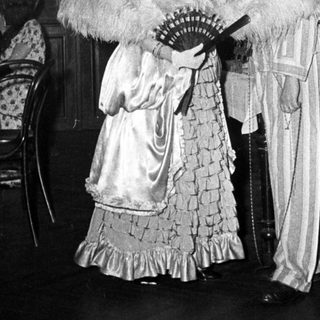 Elegant 19th-century formal attire with fans indoors.