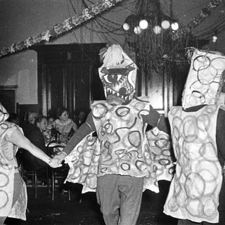 Costumed children dancing in festive indoor celebration.