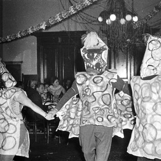 Costumed children dancing in festive indoor celebration.