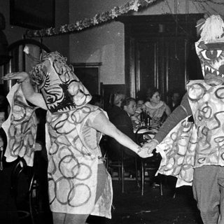 Costumed children dancing in festive indoor celebration.