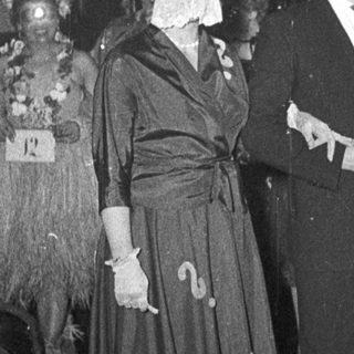 Costumed party guests wearing question-mark outfits and masks.