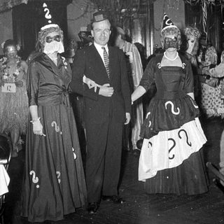Costumed party guests wearing question-mark outfits and masks.