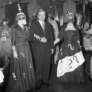 Costumed party guests wearing question-mark outfits and masks.