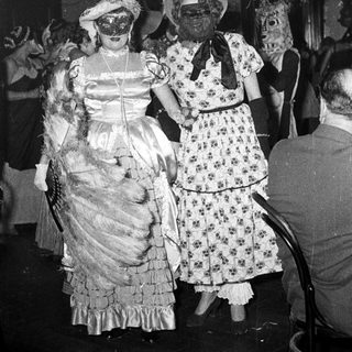 Vintage costume party with masked women in 1920s-30s attire.