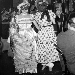 Vintage costume party with masked women in 1920s-30s attire.