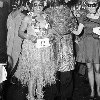 Costumed party attendees in 1950s-style tropical and glamorous outfits.