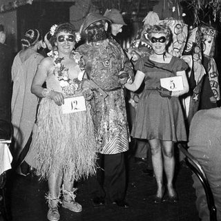 Costumed party attendees in 1950s-style tropical and glamorous outfits.