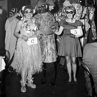 Costumed party attendees in 1950s-style tropical and glamorous outfits.