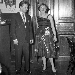 Man and woman in formal attire at event.
